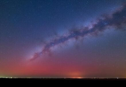 A starry night sky with the Milky Way and a red horizon glow