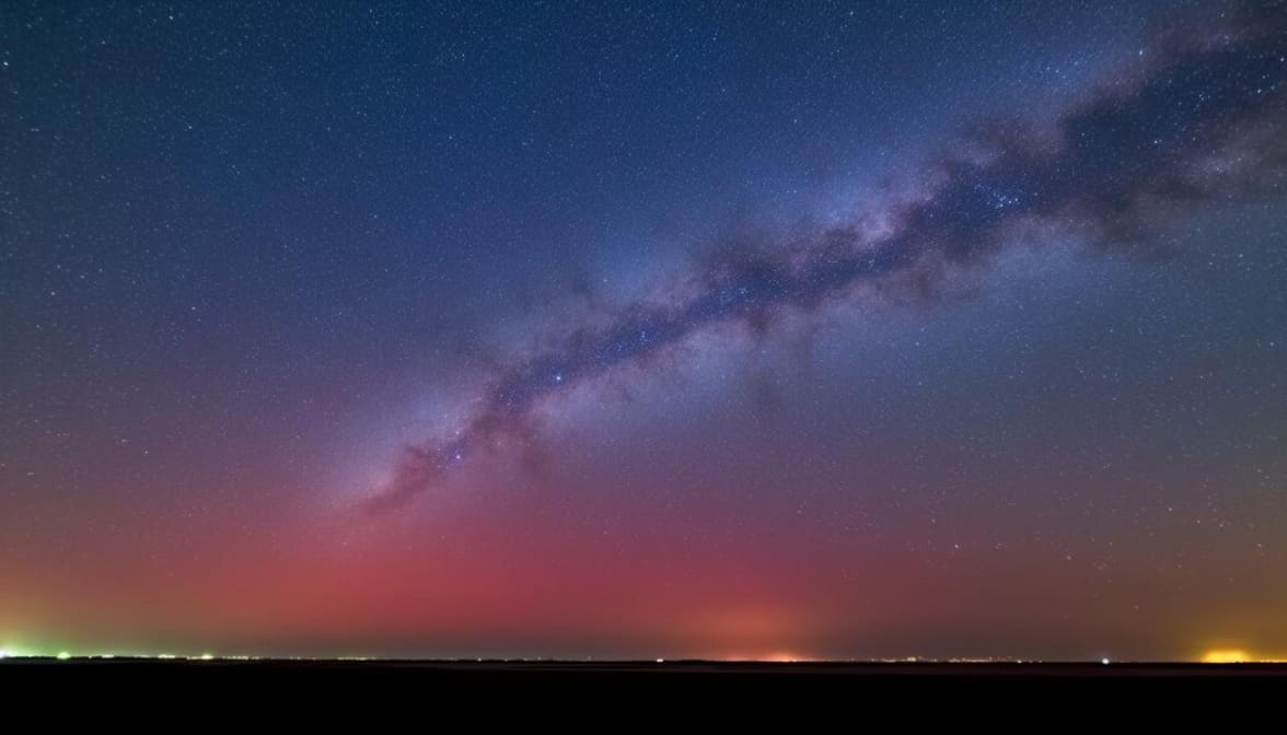A starry night sky with the Milky Way and a red horizon glow