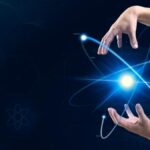Fingers poised as if manipulating a glowing blue atomic structure against a digital background