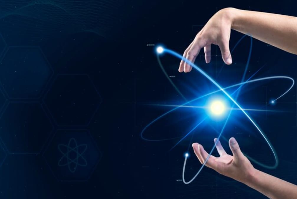 Fingers poised as if manipulating a glowing blue atomic structure against a digital background