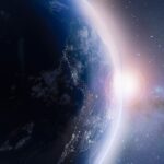 Earth viewed from space with the sun peeking over its horizon