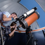 A man and a girl looking through a telescope