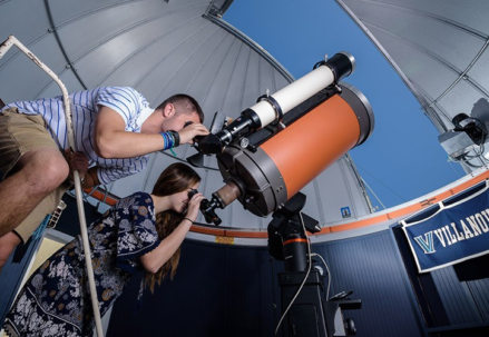 A man and a girl looking through a telescope