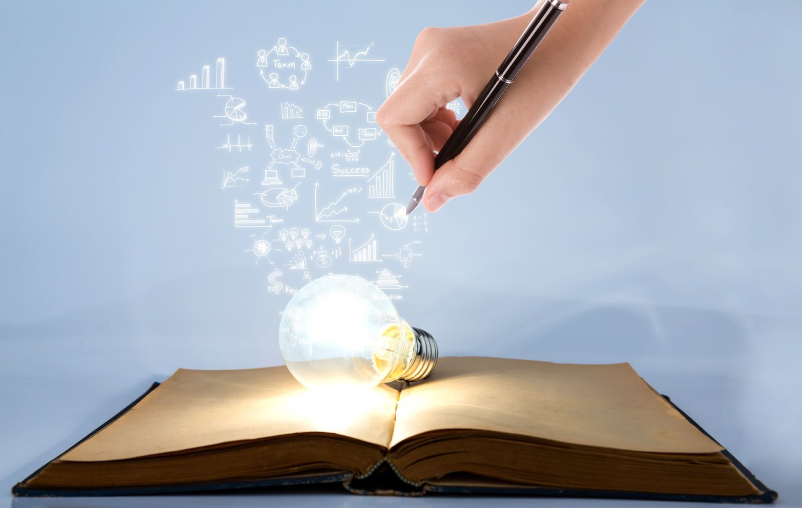 Symbols coming out of a light bulb on top of a book